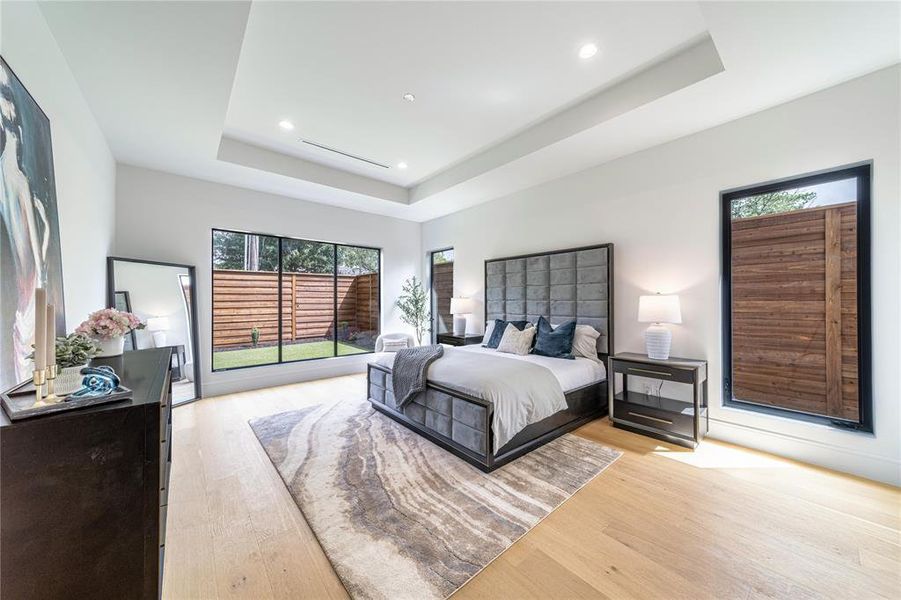 Bedroom featuring light wood-type flooring, a raised ceiling, and recessed lighting