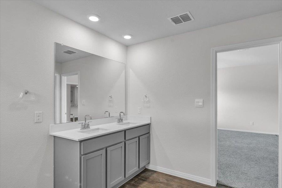 Full bathroom with double vanity and dark wood-type flooring
