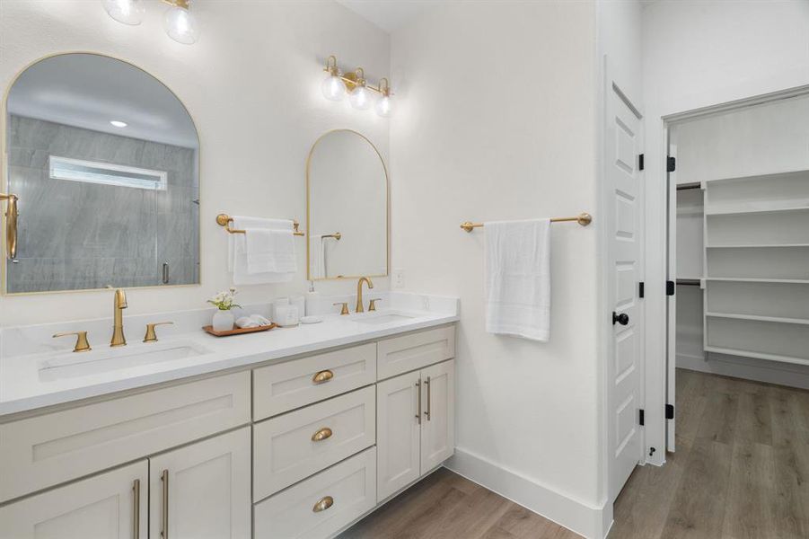 Bathroom with double vanity, a stall shower, light wood-type flooring, and a walk in closet Bathroom with double vanity, a stall shower, light wood-type flooring, and a walk in closet
