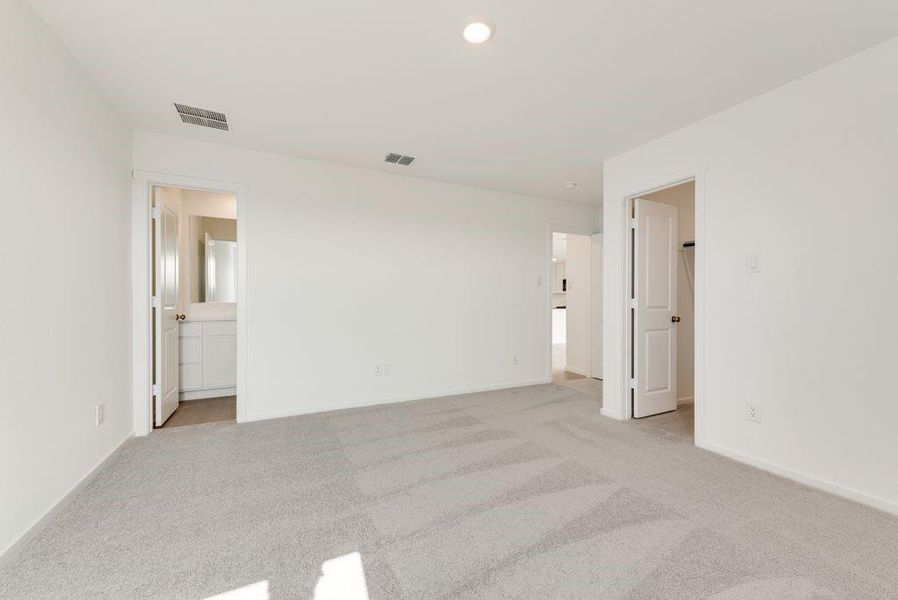 Unfurnished bedroom featuring light carpet, connected bathroom, visible vents, and baseboards