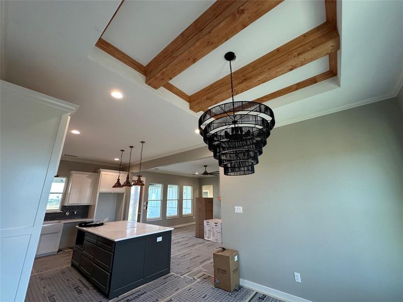 Kitchen with a center island, decorative light fixtures, decorative backsplash, white cabinets, and ceiling fan with notable chandelier