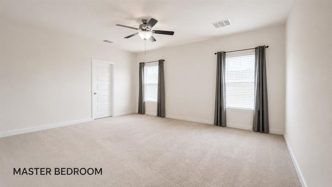 Spacious room with plush carpeting, two windows with blinds, a ceiling fan with integrated lighting, and a paneled door Spacious room with plush carpeting, two windows with blinds, a ceiling fan with integrated lighting, and a paneled door