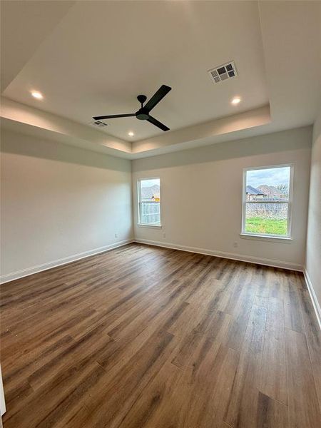 Spare room featuring dark wood-type flooring, a tray ceiling, a ceiling fan, and recessed lighting