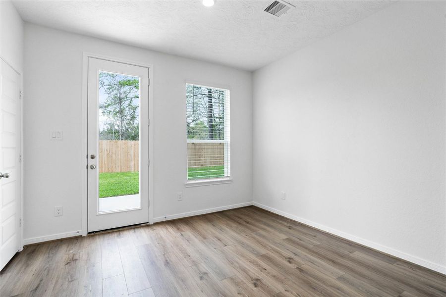Start your day with a warm cup of coffee and quality time in this charming breakfast nook! Highlights include a large window with blinds, custom neutral paint, vinyl plank flooring, recessed lighting, high ceilings, and a convenient door leading to the rear patio and backyard.