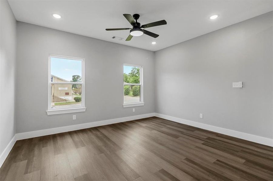 Empty room with ceiling fan and dark hardwood / wood-style flooring