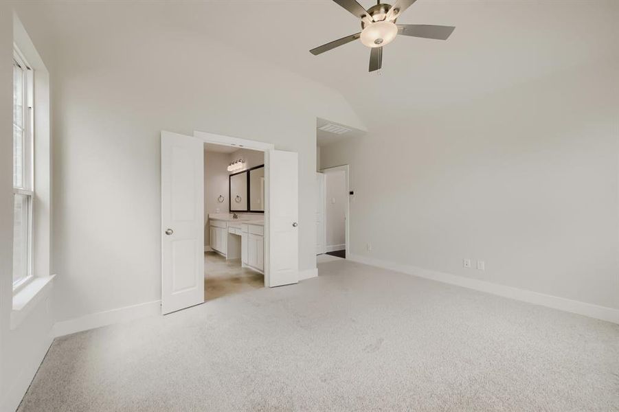 Spacious room featuring vaulted ceilings, light-colored carpet, and an overhead ceiling fan