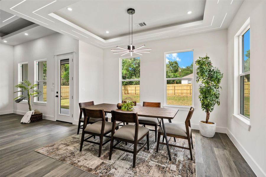 Dining area with high ceilings featuring a contemporary chandelier, recessed lighting, and tray ceiling details