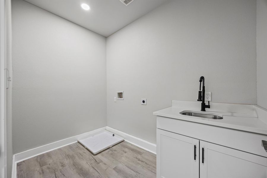 Laundry area with light wood-type flooring, cabinet space, washer hookup, electric dryer hookup, and recessed lighting Laundry area with light wood-type flooring, cabinet space, washer hookup, electric dryer hookup, and recessed lighting