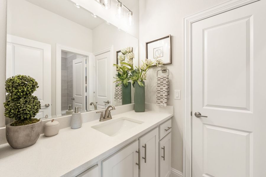 Bathroom vanity with white cabinets, quartz countertop, single sink, and large mirror with overhead lighting