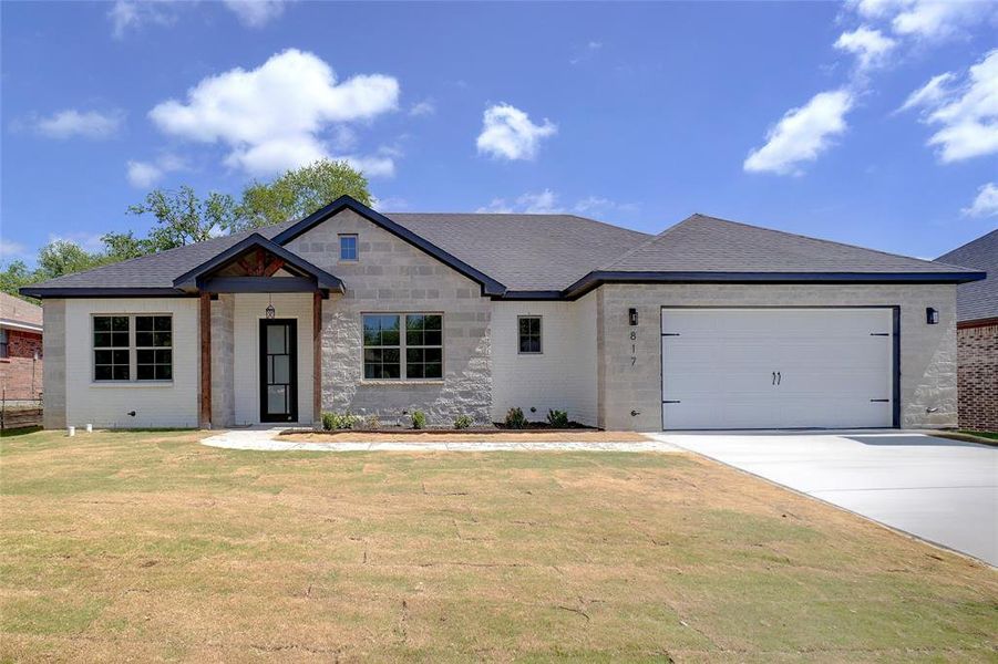 View of front facade with driveway, an attached garage, a front yard, roof with shingles, and stone siding View of front facade with driveway, an attached garage, a front yard, roof with shingles, and stone siding