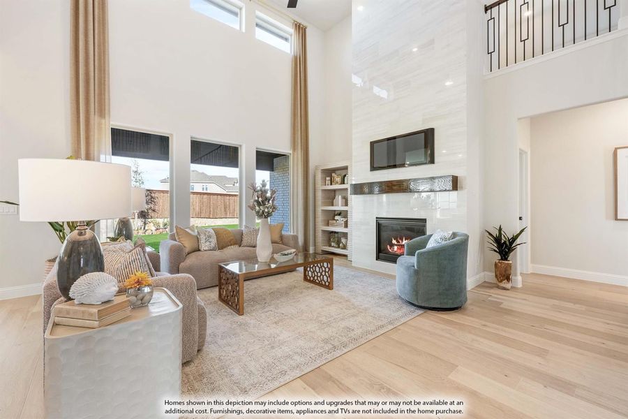 Living room with two-story ceiling, tile fireplace, hardwood floors, and built-in shelving