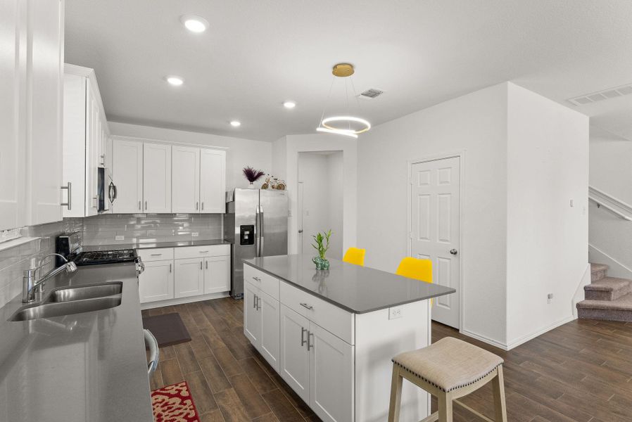 Kitchen with white cabinetry, hanging light fixtures, appliances with stainless steel finishes, a center island, and dark countertops