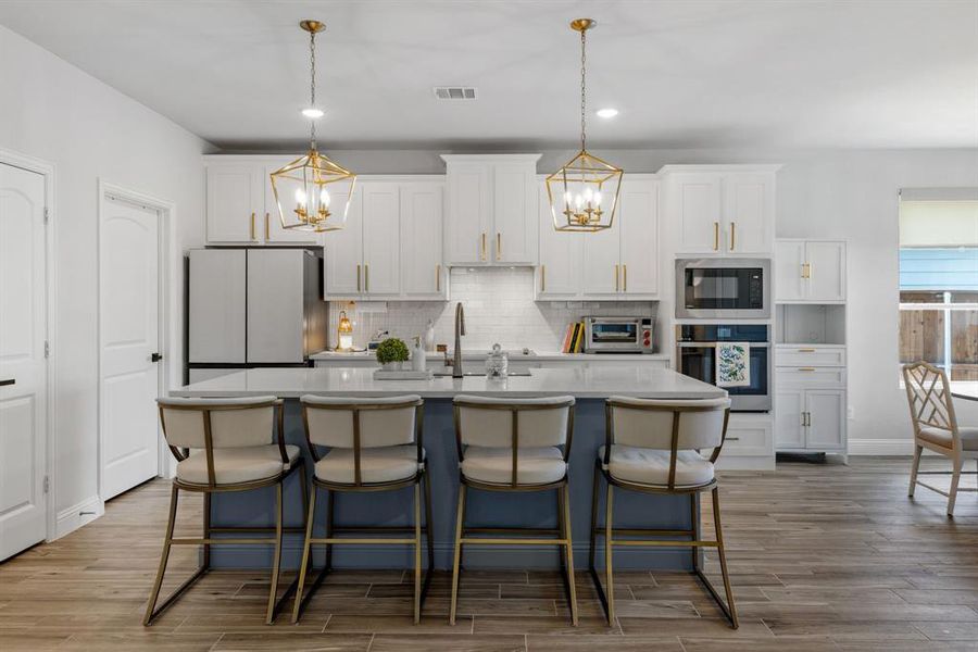 Kitchen featuring a breakfast bar area, light wood finished floors, white cabinets, recessed lighting, and stainless steel appliances