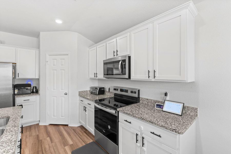 White cabinetry, granite counters, and stainless steel appliances outfit this well-appointed kitchen. White cabinetry, granite counters, and stainless steel appliances outfit this well-appointed kitchen.