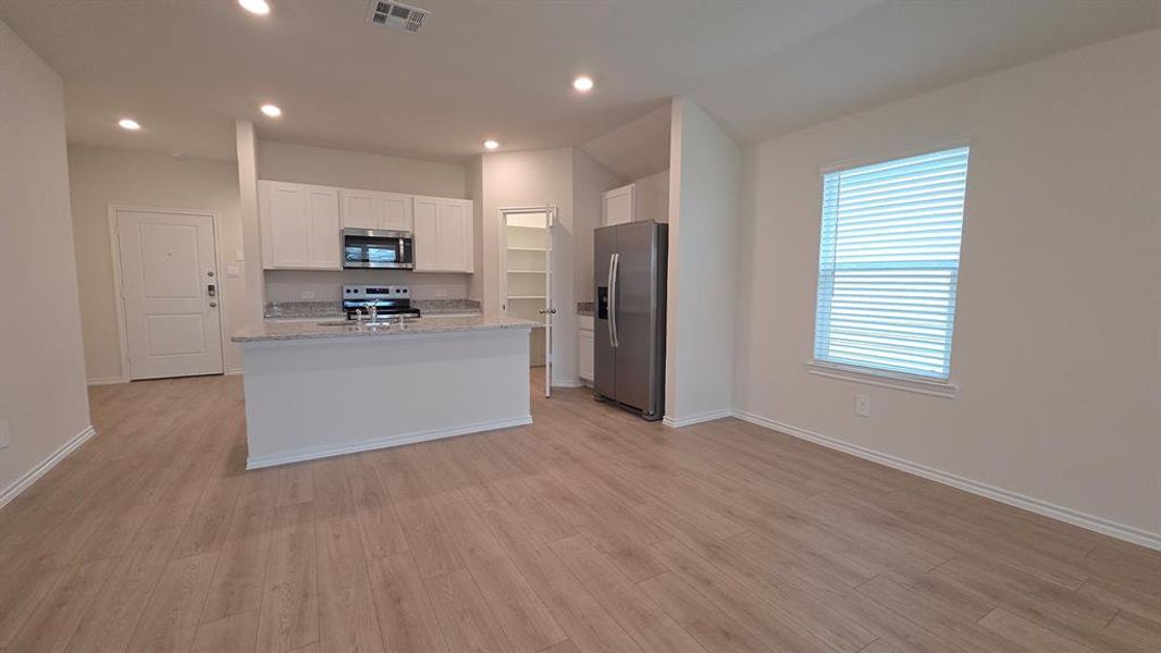 Open-concept living space with wood-finish flooring, recessed lighting, and a kitchen island featuring a breakfast bar