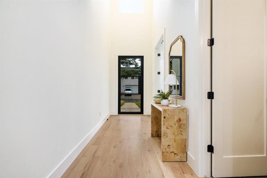 Corridor featuring a towering ceiling and light hardwood / wood-style floors