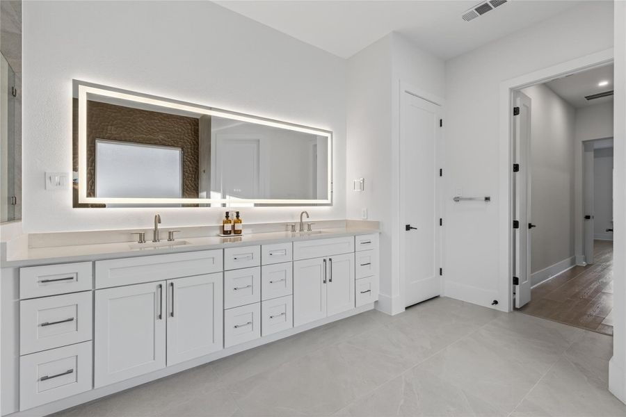 Expansive double vanity provides abundant storage and counter space beneath a large illuminated mirror. **Images are from a previously completed project. **