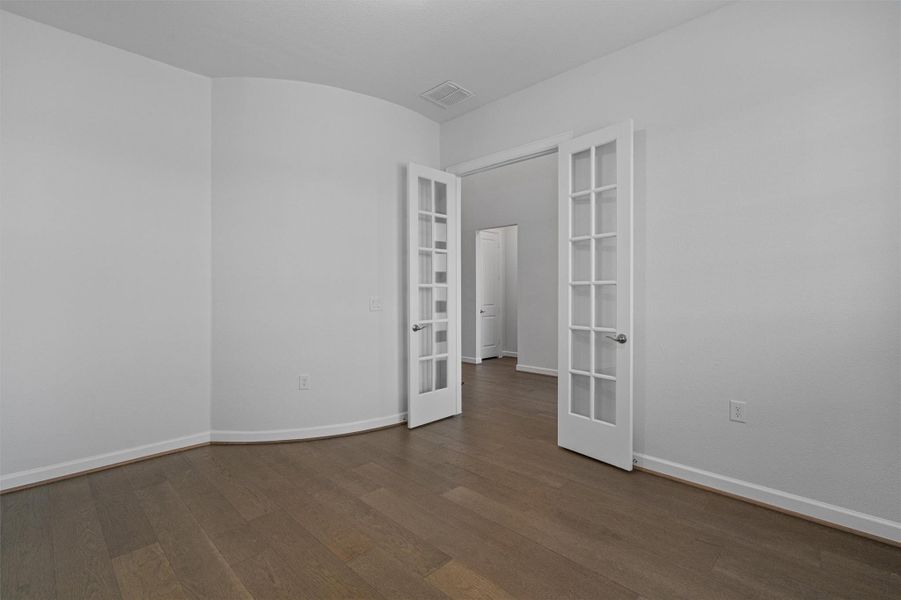 Empty room with dark wood-style flooring and french doors Empty room with dark wood-style flooring and french doors