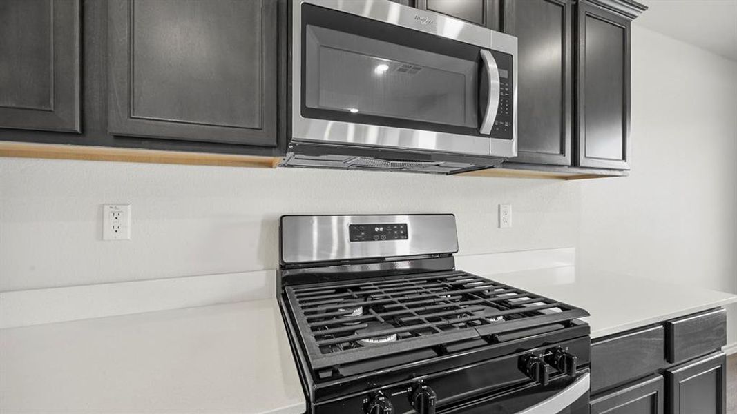 Kitchen view of stainless steel appliances and light stone counters