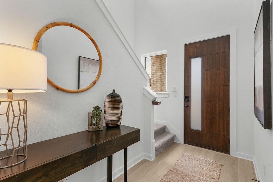 Foyer entrance with light wood-style flooring, stairway, and baseboards
