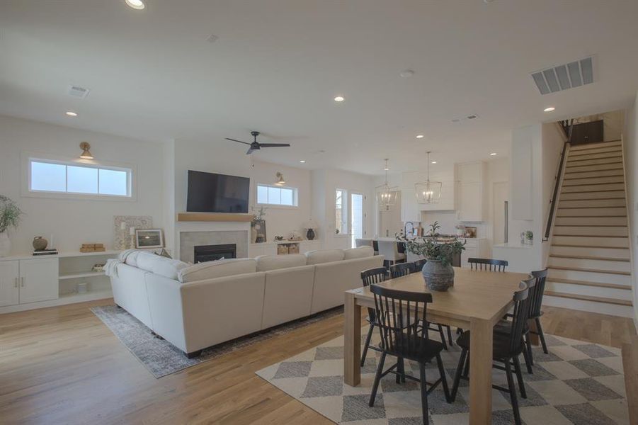 Dining space with ceiling fan, light hardwood / wood-style flooring, and a tiled fireplace