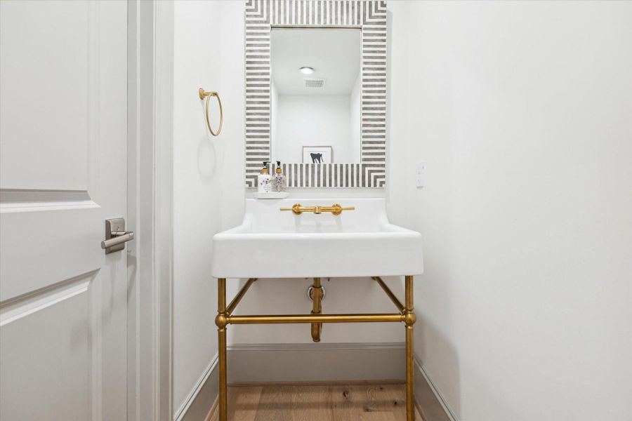 Powder Bath features console sink with brass details.
