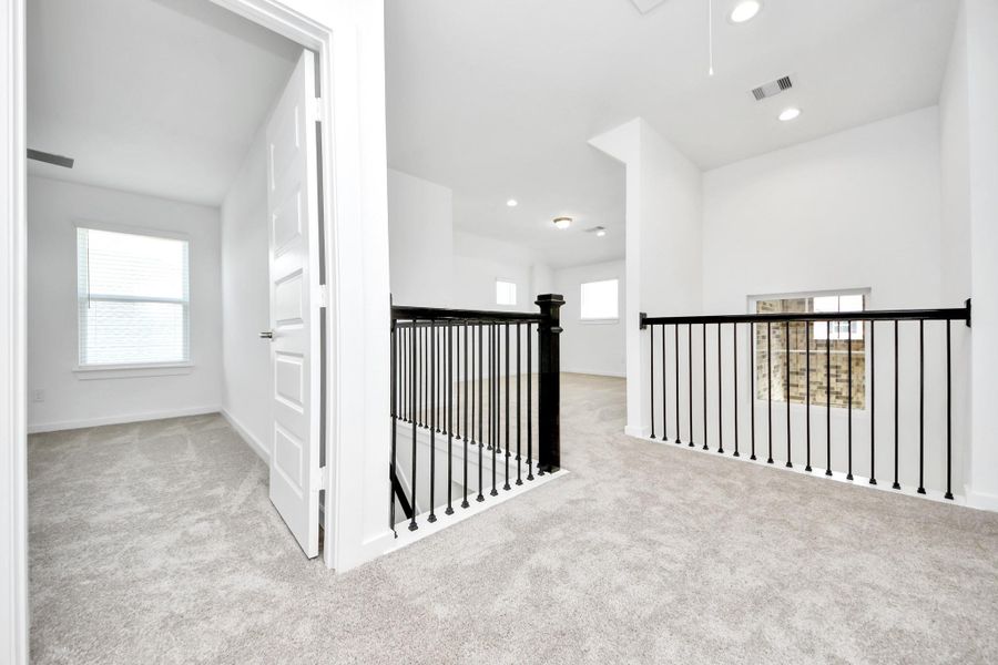 Come upstairs and relish a day of relaxation in this loft area! Ideal as an additional living space or game room, it boasts plush carpeting, high ceilings, custom paint, and windows that flood the area with abundant natural light.