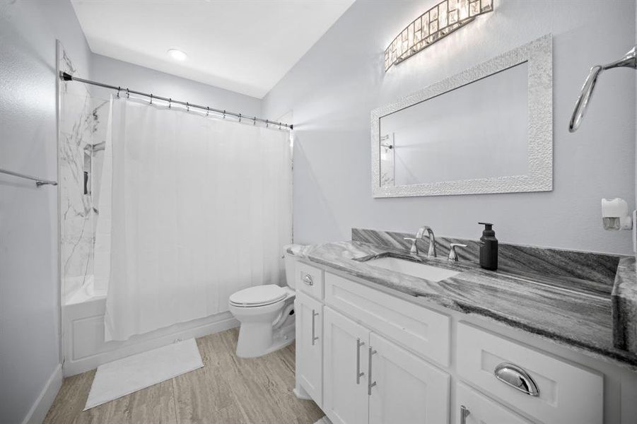 Bathroom featuring vanity, shower / bath combo with shower curtain, and light wood-style floors