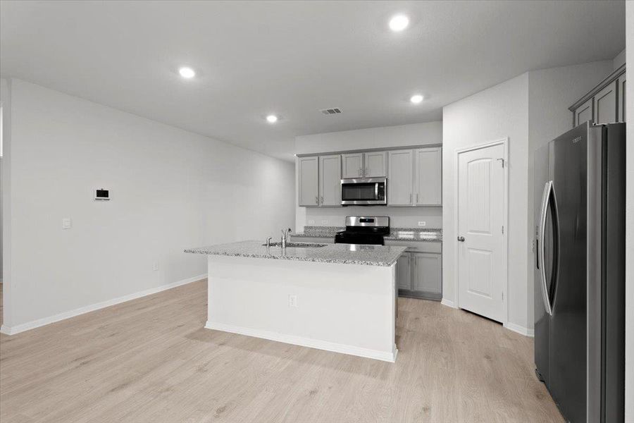 Kitchen island featuring a granite-style countertop and undermount sink