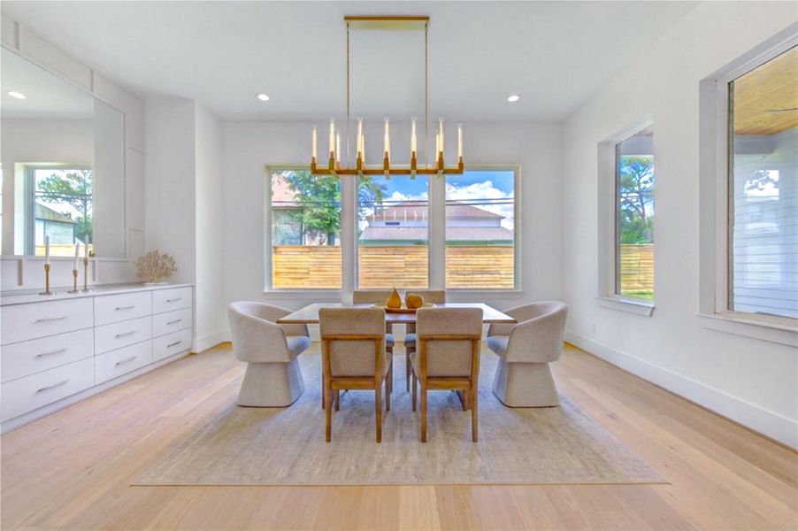 Bright and inviting dining area highlighted by designer lighting and walls of windows overlooking the outdoor living spaces.