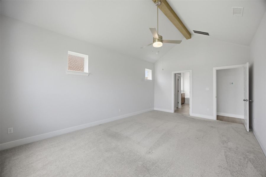 A spacious primary bedroom with soaring vaulted ceilings and a modern ceiling fan for optimal comfort.