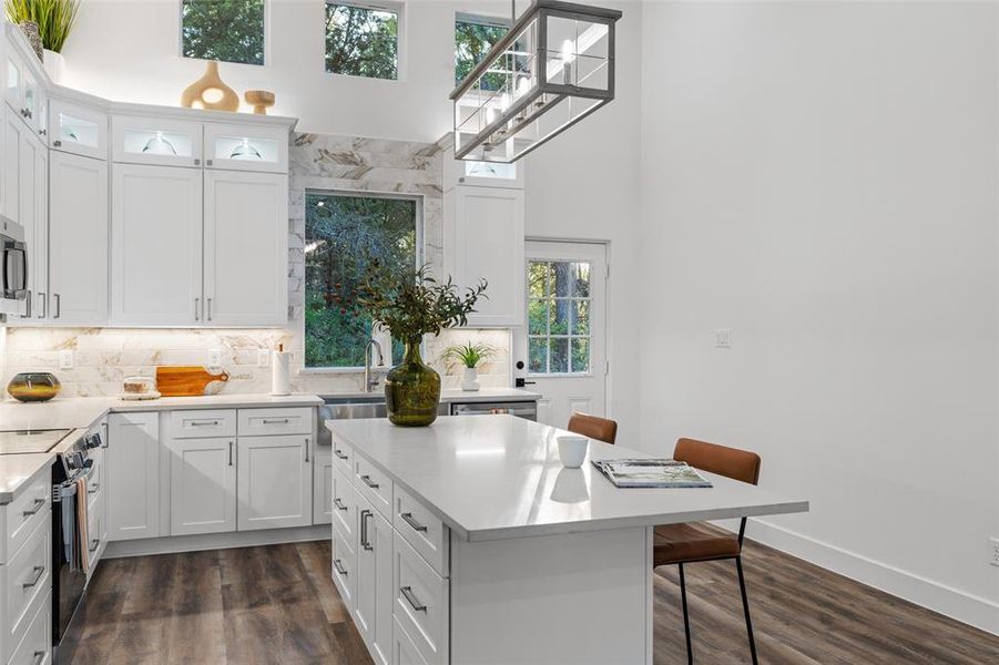 Kitchen with a kitchen breakfast bar, white cabinetry, a center island, and dark wood-type flooring