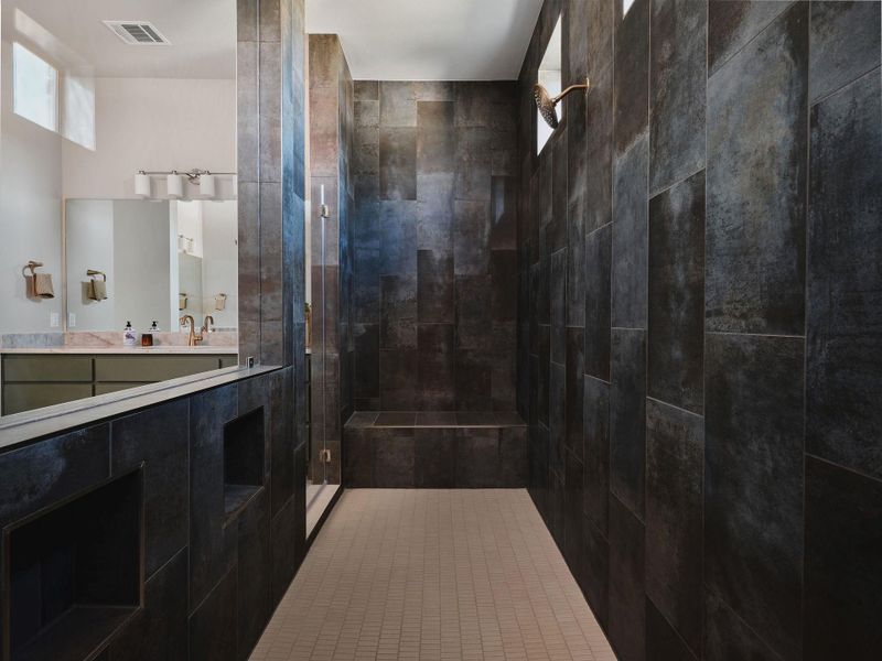 The dramatic walk-through shower features dual shower heads and a bench.