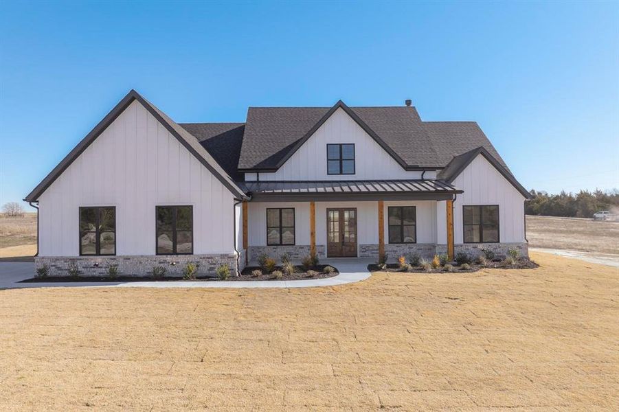 Modern farmhouse featuring covered porch and a front lawn