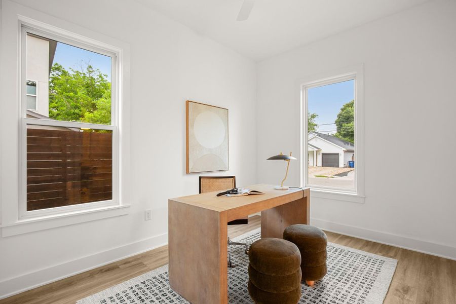 Home office featuring light wood-type flooring, a ceiling fan, and baseboards