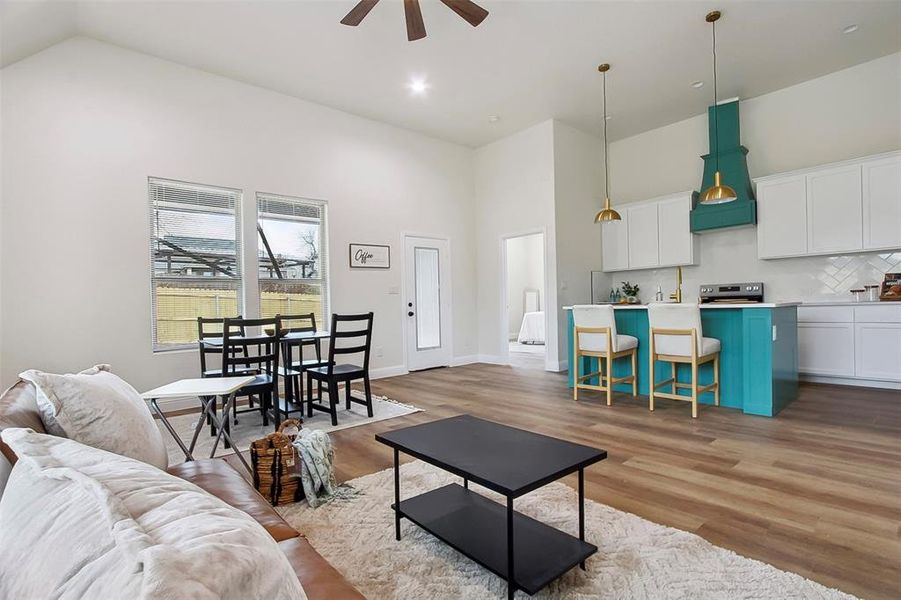 Living room featuring ceiling fan, high vaulted ceiling, and light hardwood / wood-style flooring