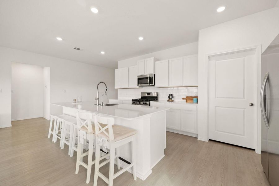 A well-lit culinary space features bright white cabinetry and an inviting island with seating.