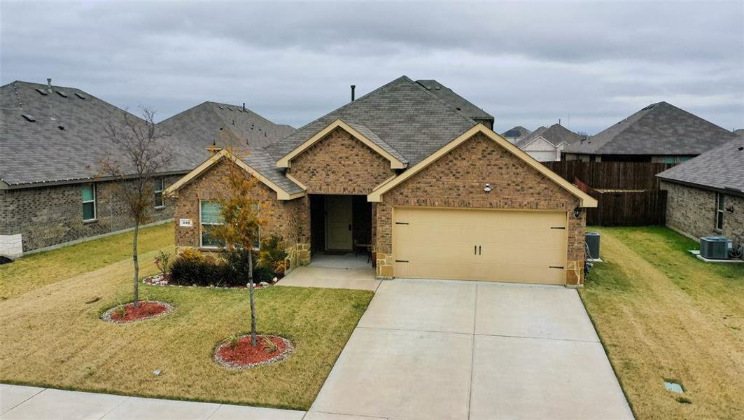 View of front of home with central AC unit, a front yard, and a garage