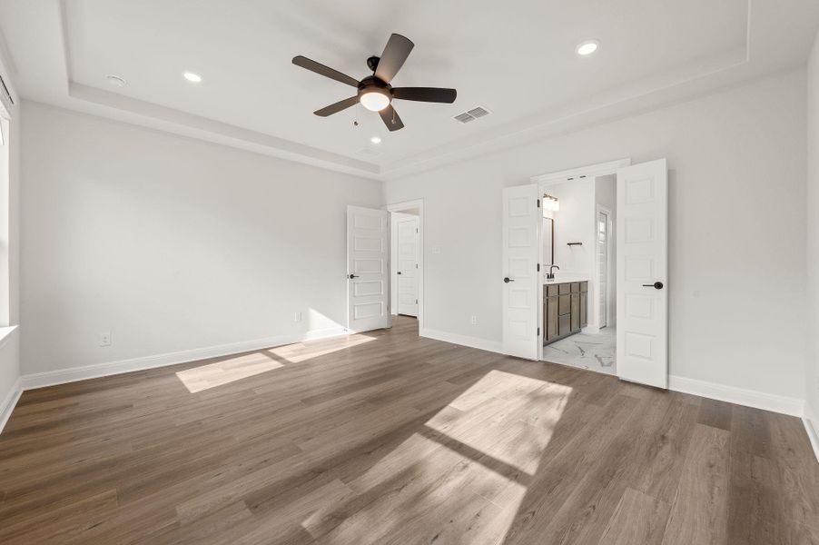 Primary bedroom with tray ceilings and ensuite bath