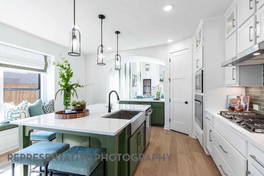 Kitchen with green cabinets, appliances with stainless steel finishes, a sink, an island with sink, and recessed lighting Kitchen with green cabinets, appliances with stainless steel finishes, a sink, an island with sink, and recessed lighting