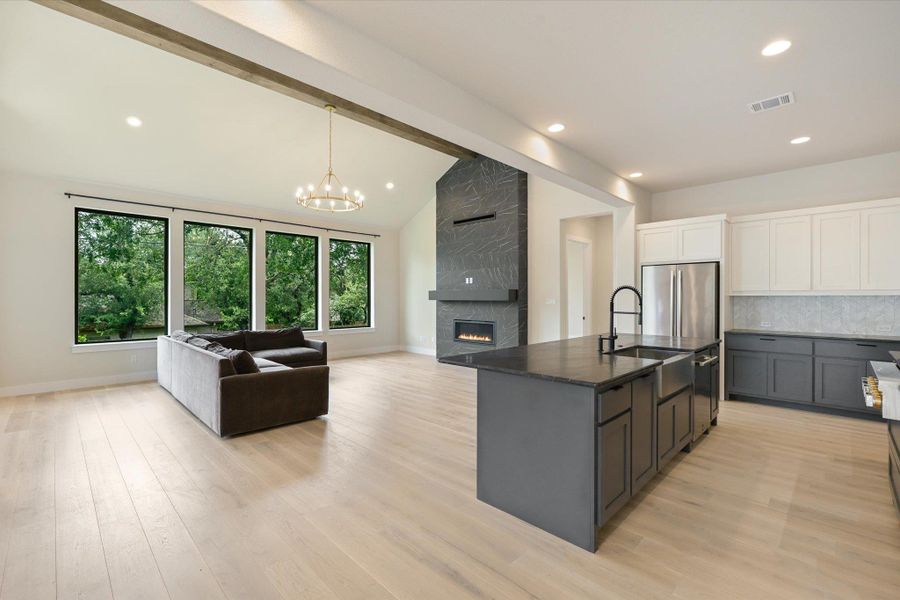 An open concept living area showcases vaulted ceilings, a modern fireplace, and a large kitchen island.