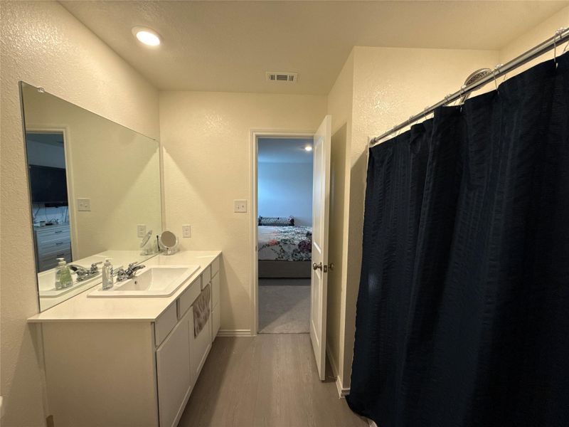 Bathroom featuring a single vanity with an integrated sink, polished chrome faucet, and a large wall-mounted mirror