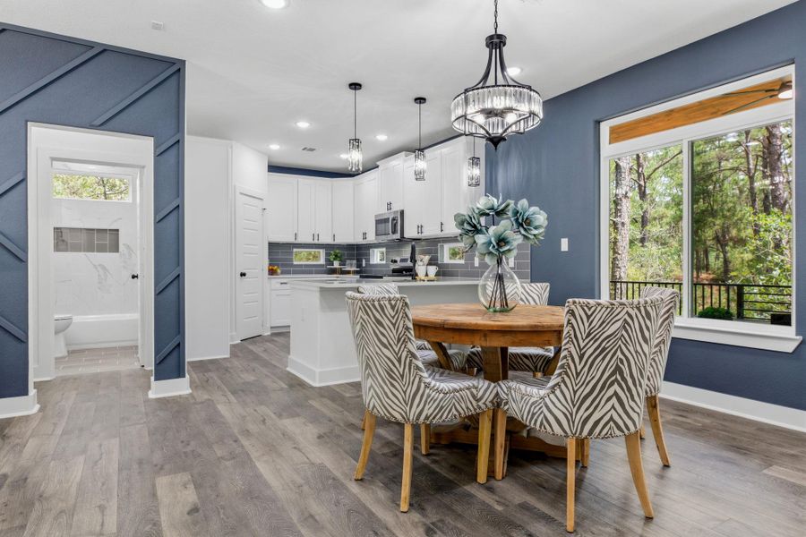 An open concept design seamlessly connects the kitchen and dining areas, with a large window framing the natural surroundings.
