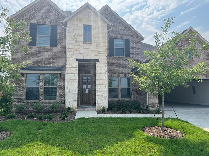 French country style house featuring concrete driveway, a front yard, and brick siding