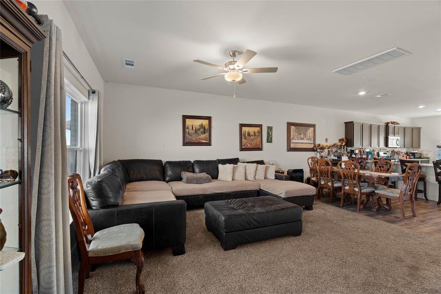 Carpeted living room with ceiling fan and recessed lighting