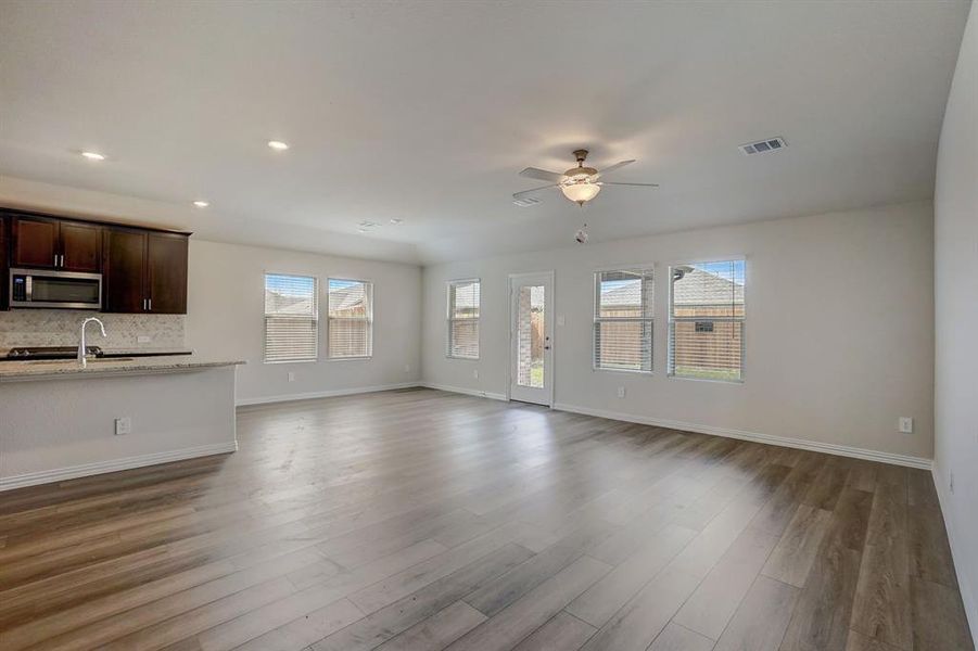 Unfurnished living room with sink, light wood-type flooring, and ceiling fan