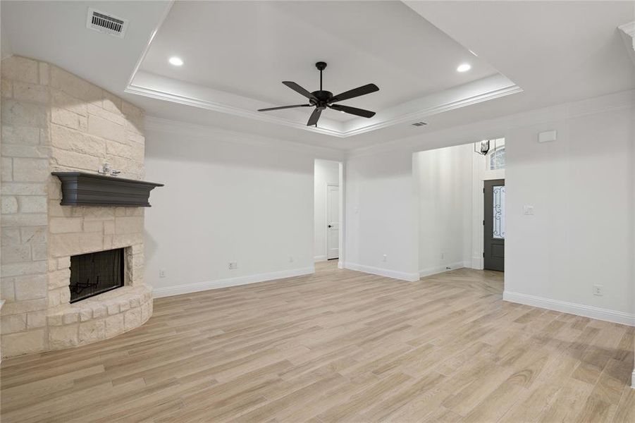 Unfurnished living room with crown molding, light hardwood / wood-style floors, and a raised ceiling