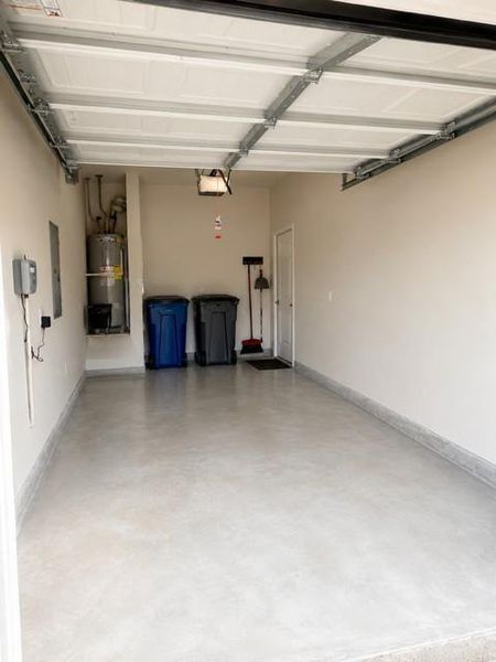 Spacious garage featuring a light gray concrete floor, white painted walls, and a white overhead garage door Spacious garage featuring a light gray concrete floor, white painted walls, and a white overhead garage door