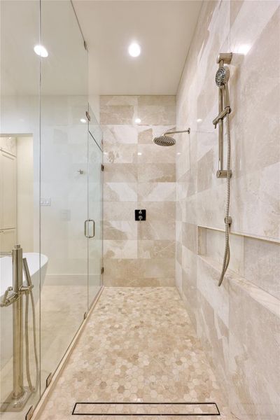 Spacious walk-in shower adorned with limestone and marble mosaic tile, creating a luxurious and visually striking design. Spacious walk-in shower adorned with limestone and marble mosaic tile, creating a luxurious and visually striking design.