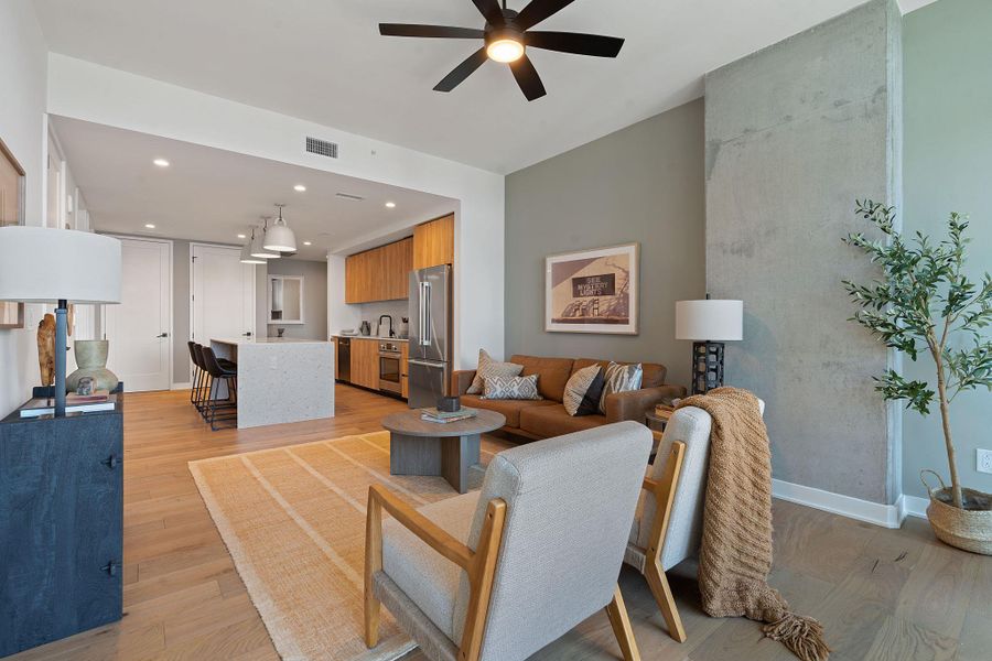 Representative Photo. Open Concept living room with 7.5" wide Bella Cera hardwood flooring, recessed lighting, ceiling fan, and a balcony off the living room with a West view